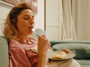 Mujer embarazada sonriendo en la cocina comiendo antojo dulce