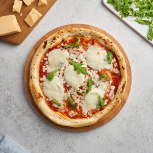 Receta de Pizza Margarita Fácil con Pan Árabe Pizza margarita en el centro con decoración de queso y albahaca alrededor