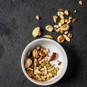 Desayuno saludable con yogurt, nueces y plátano Bowl blanco con varios frutos secos dentro