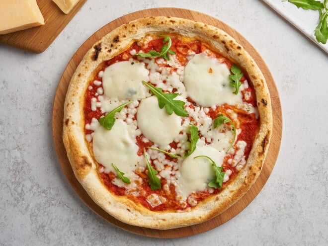 Receta de Pizza Margarita Fácil con Pan Árabe Pizza margarita en el centro con decoración de queso y albahaca alrededor