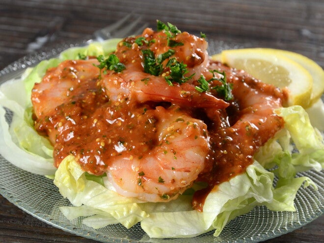 Pescado y Ensalada Criolla en un plato hay una base de ensalada y encima camarones con salsa