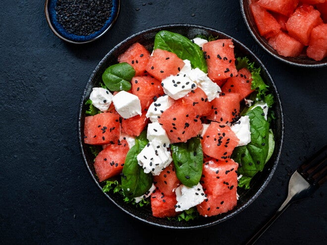 Ensalada de Sandía, Espinacas y Queso con Pan Un bowl que contiene cubos de sandía, espinacas y queso