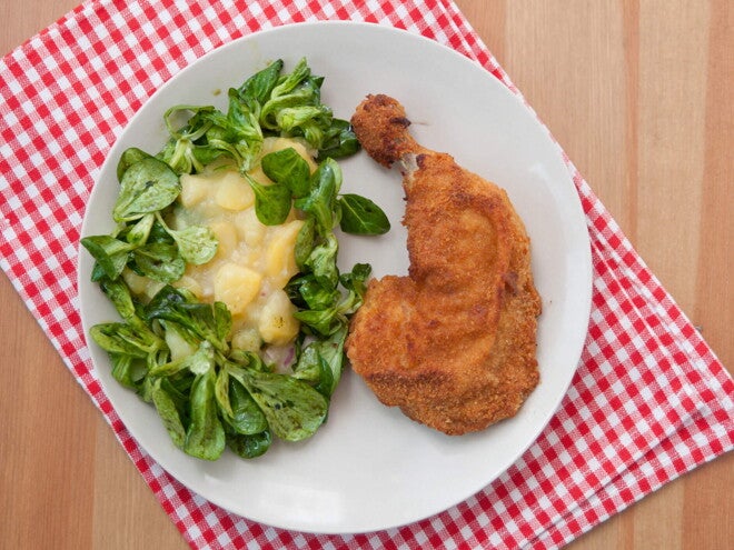 Un plato que contiene pollo empanizado con una ensalada