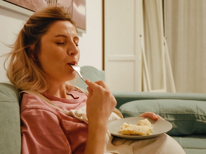 Mujer embarazada sonriendo en la cocina comiendo antojo dulce