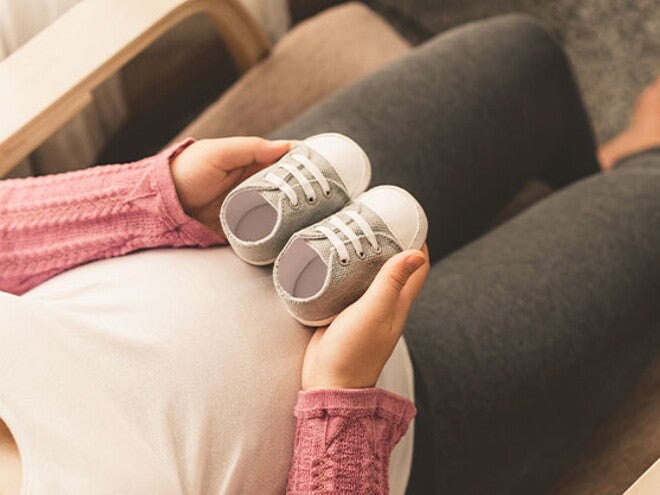 Conoce qué es el bebé arcoíris. Mamá embarazada de un bebé arcoíris cogiendo unos zapatitos.