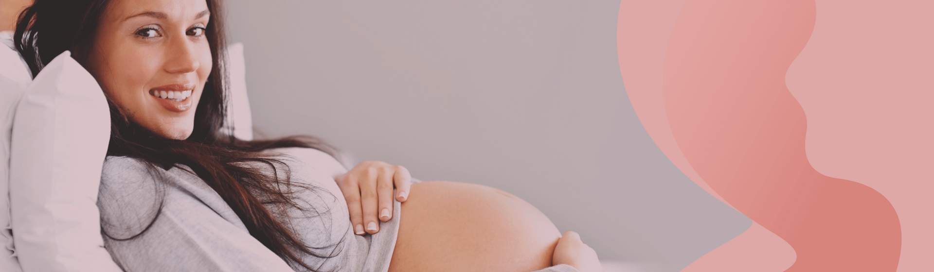 Pregnant woman reclined on her bed wtih some pillows, looking and smiling at the camera. Pregnant woman reclined on her bed wtih some pillows, looking and smiling at the camera.