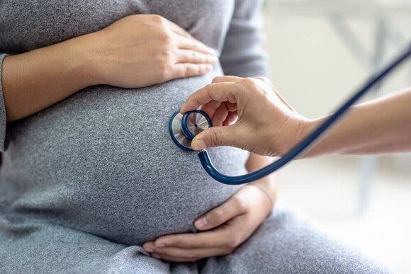 Médico revisando a una mujer embarazada durante una consulta prenatal
