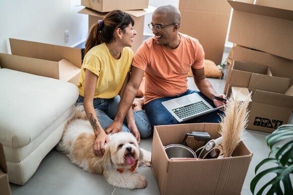 Pareja feliz con su perro planificando su futuro en un nuevo hogar, etapa previa a cómo quedar embarazada.